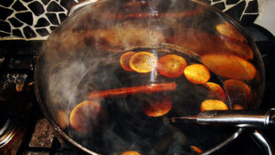 Image of at of steaming mulled wine with cinnamon sticks and orange peel