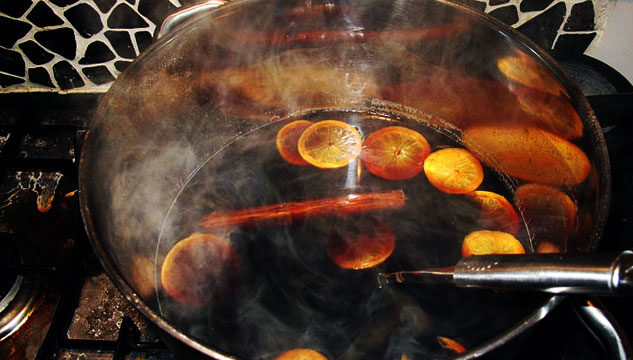 Image of at of steaming mulled wine with cinnamon sticks and orange peel