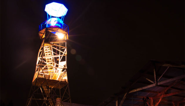 Image of illuminated inland lighthouse at night.