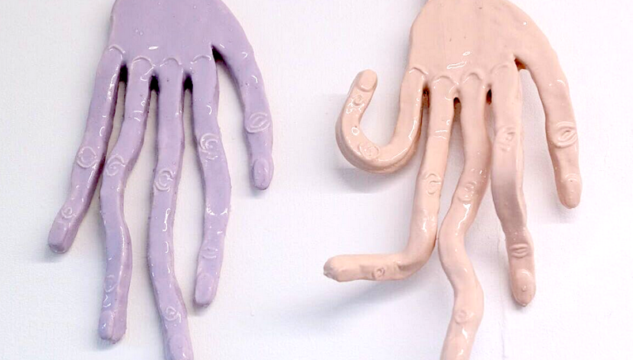 two hands made of flat pastle coloured rubber with very long fingers
