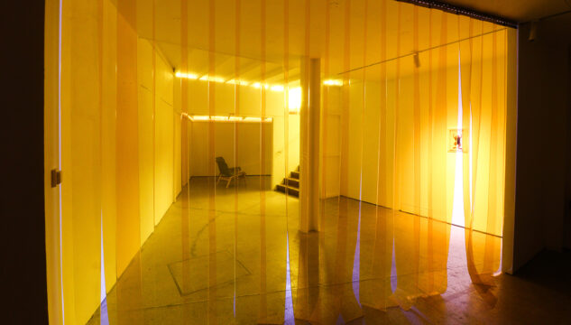 looking through yellow see through curtain into empty gallery space