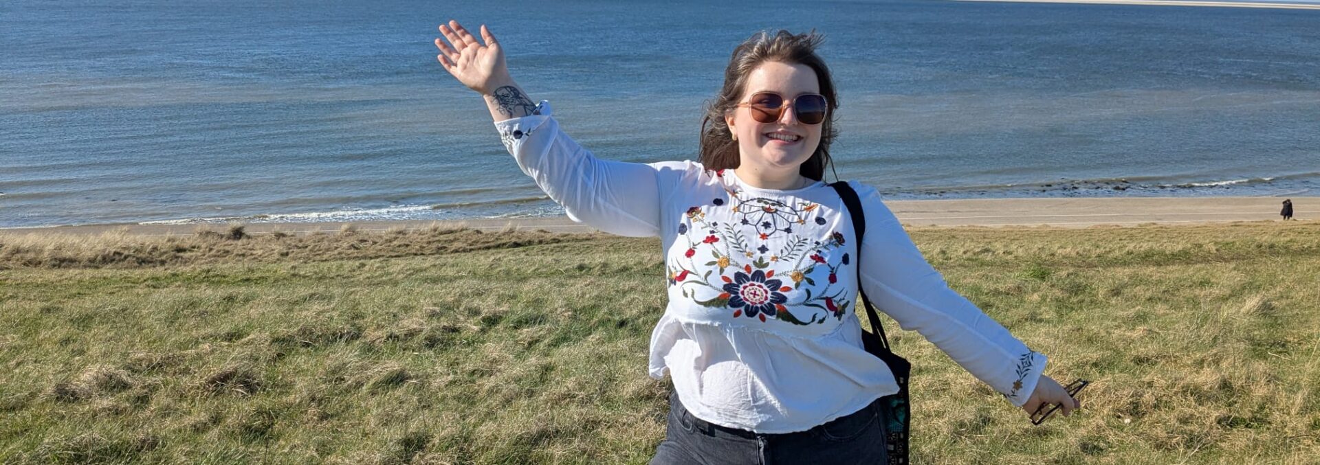 A young woman stood in a grassy field overlooking the sea