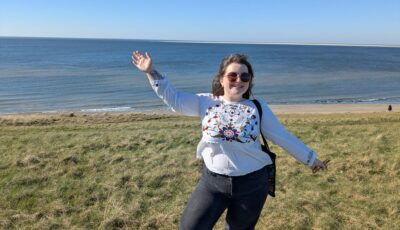 A young woman stood in a grassy field overlooking the sea