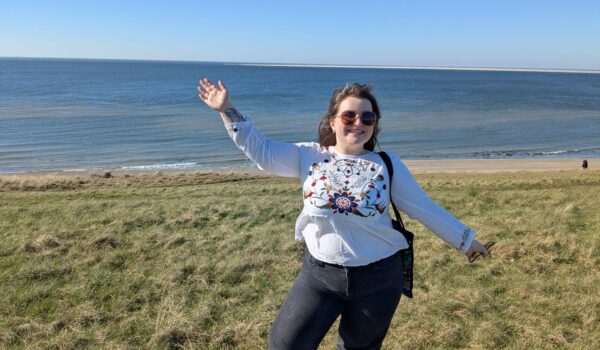 A young woman stood in a grassy field overlooking the sea