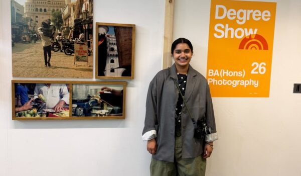 a young woman stood infront of a white wall. Artwork is on either side of her.