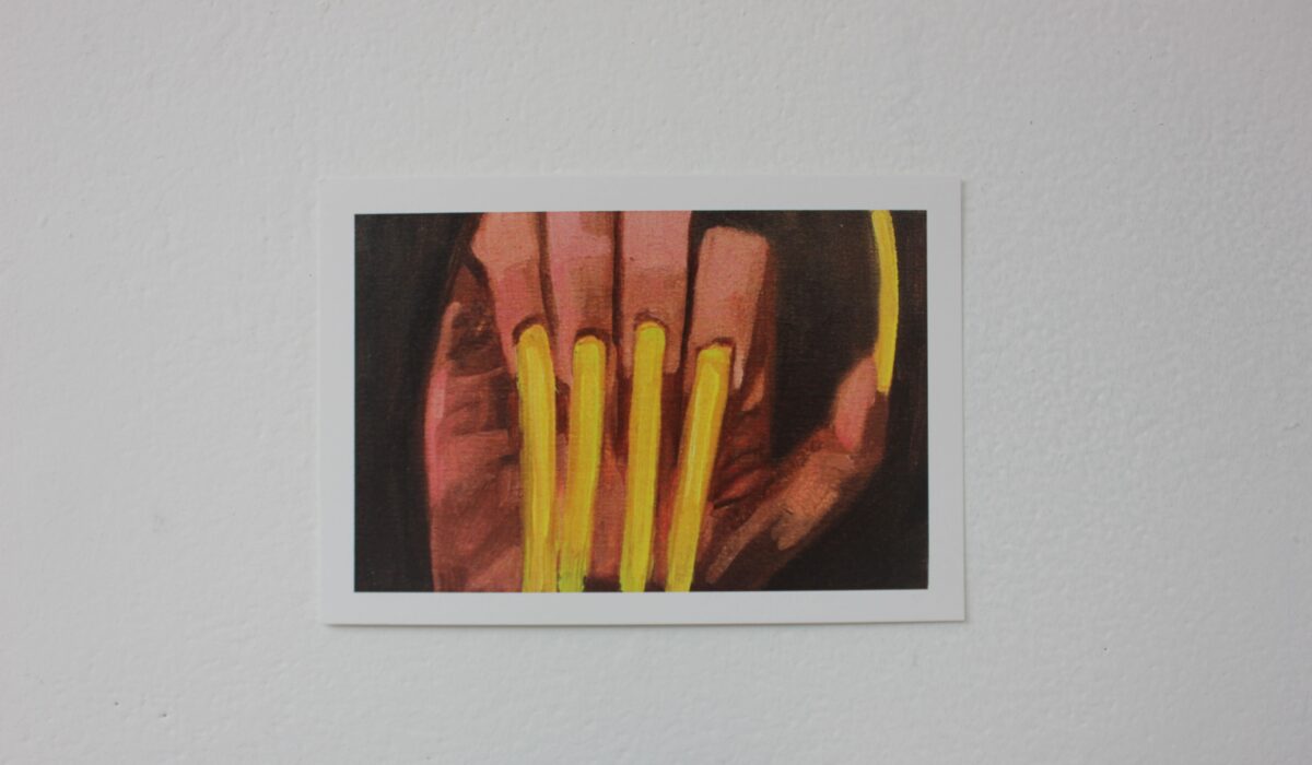 Postcard of a hand with long, yellow acrylic nails, set against a black background.