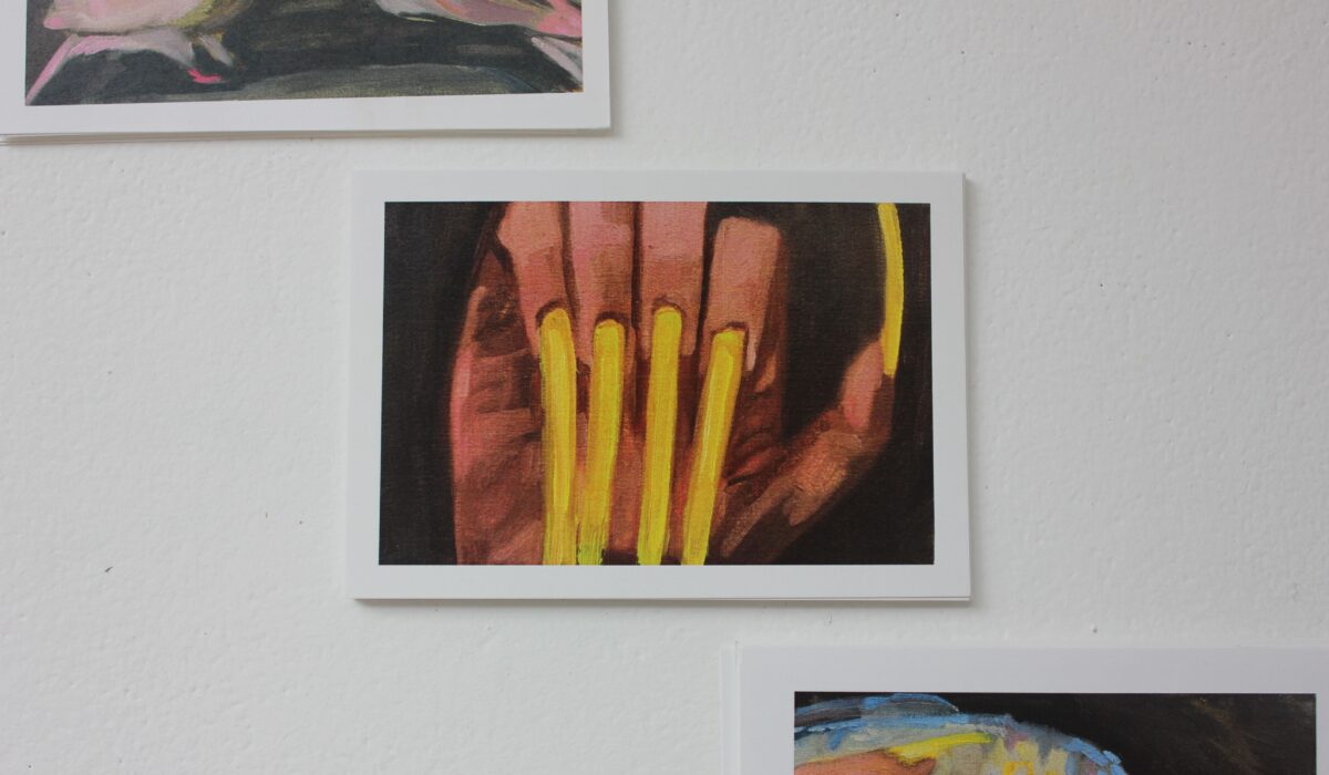 Close-up of three postcards of two pigeons, acrylic nails, and a fish, displayed in diagonal formation.