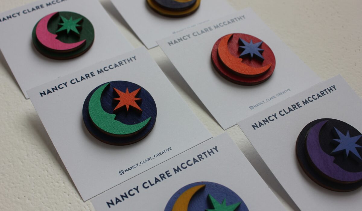 Multiple wooden brooches laid out in pairs against white background.